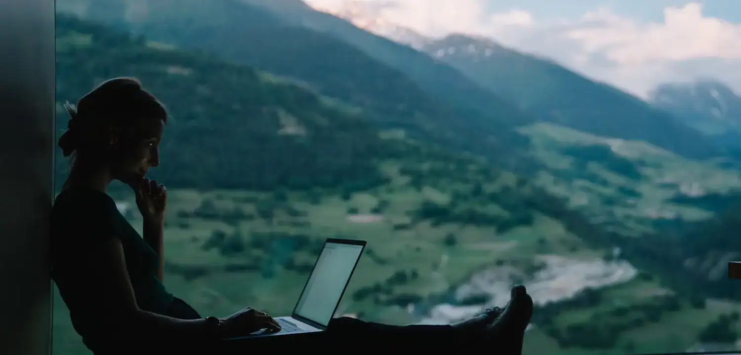 Female working on laptop with mountain view background, innovative business and digital marketing concept.
